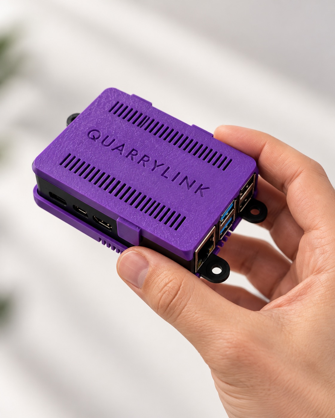 A hand holding the QuarryLink Edge device — a small on-site unit that connects a weighbridge to QuarryLink